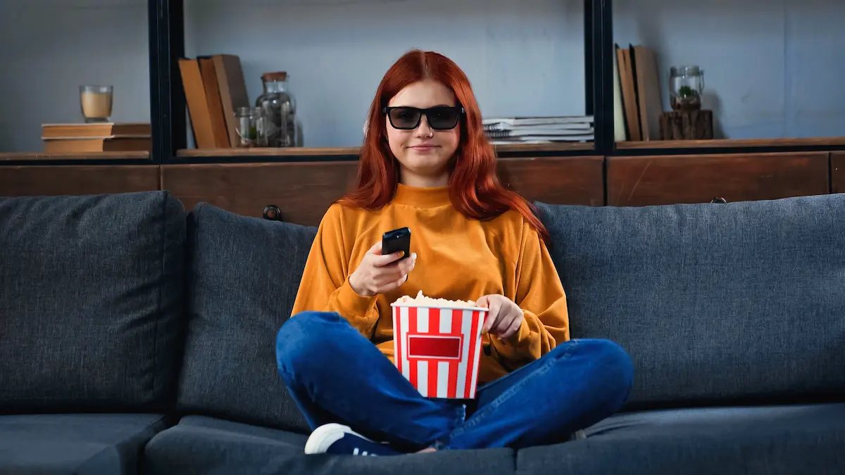 Руда дівчина з попкорном дивиться фільм